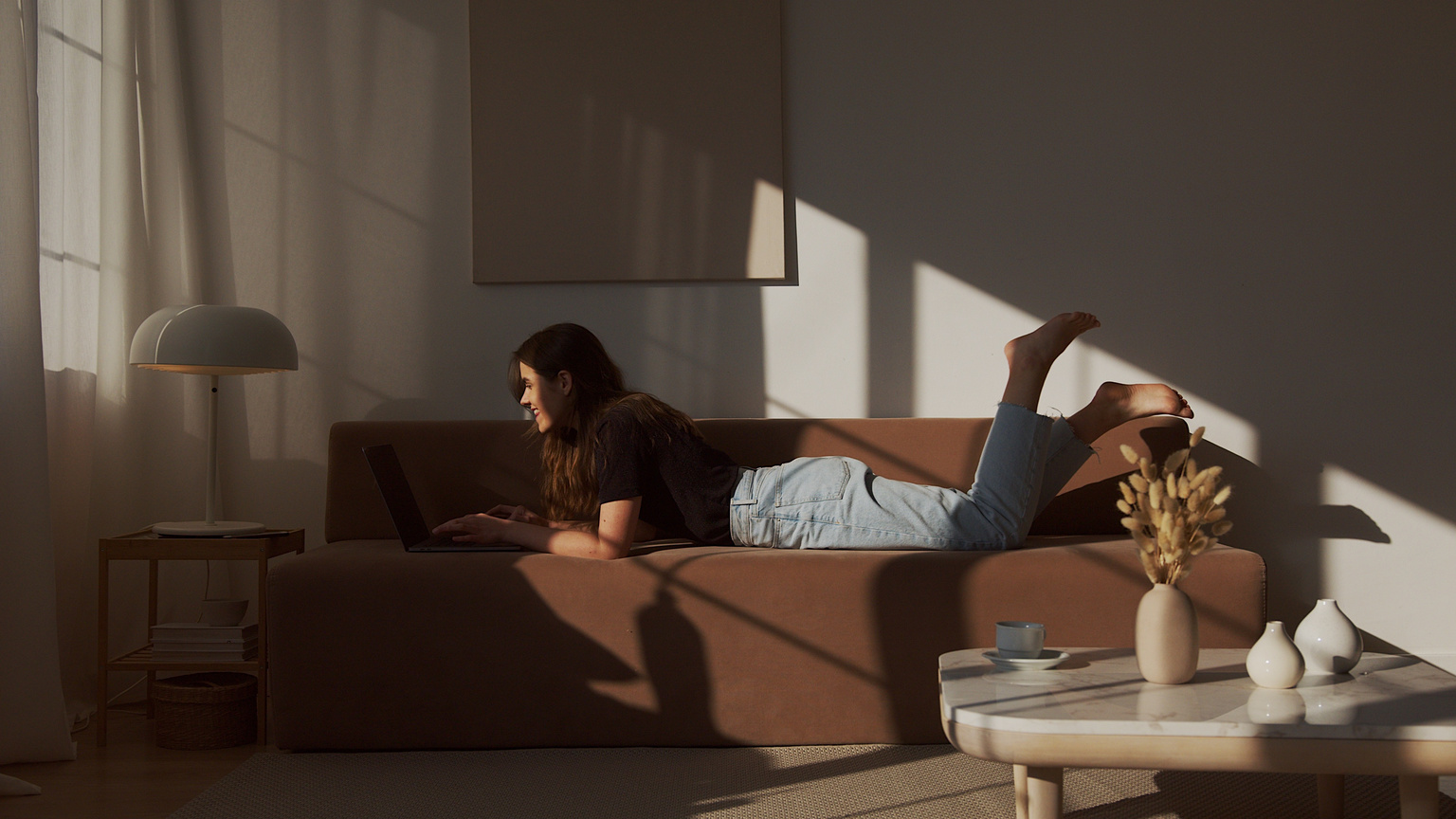 Smiling woman chilling on couch with laptop